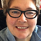 headshot of a woman with short, brown hair with black glasses