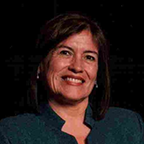 headshot of a smiling woman with shoulder-length, brown hair. she is wearing a dark green blue blouse