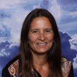 headshot of a woman with long hair and smiling in front of a background with clouds on it