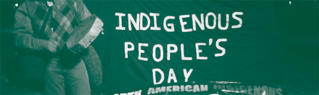 image of a person standing next to a poster that says 'indigenous people's day'