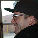 side profile of a man with glasses and a baseball cap
